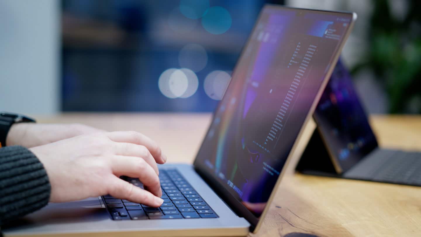 Ruky píšu na notebooku zobrazujúcom dáta a grafy.